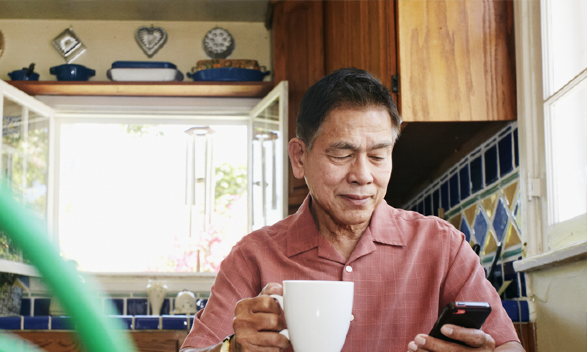 Person holding a mug whilst looking at mobile phone