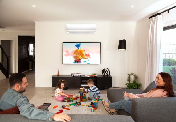 Family enjoying a comfortable indoor living space with a wall-mounted heating and cooling system and children playing in the centre of the room.