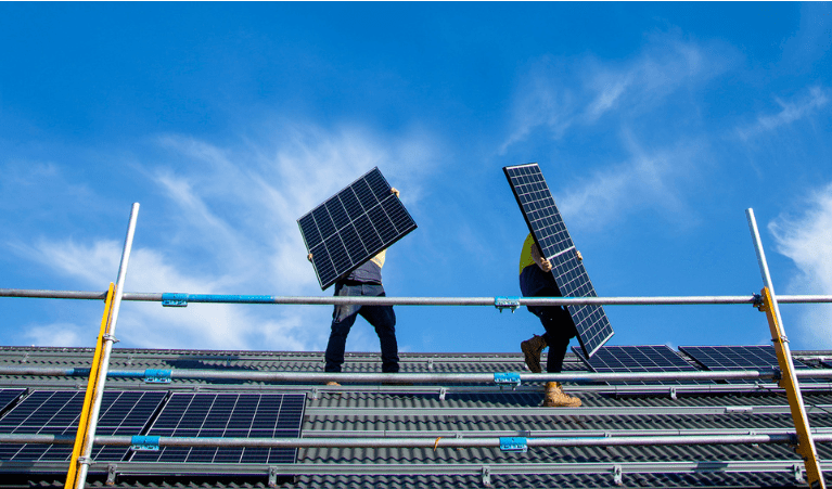 People installing solar panels on house roof