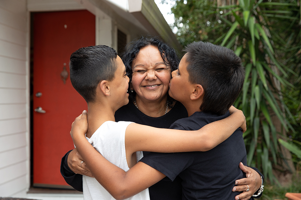 A mother and two children outside a house
