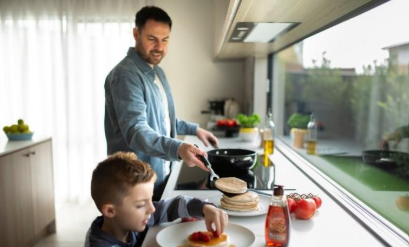 Adult and boy cooking pancakes in kitchen  