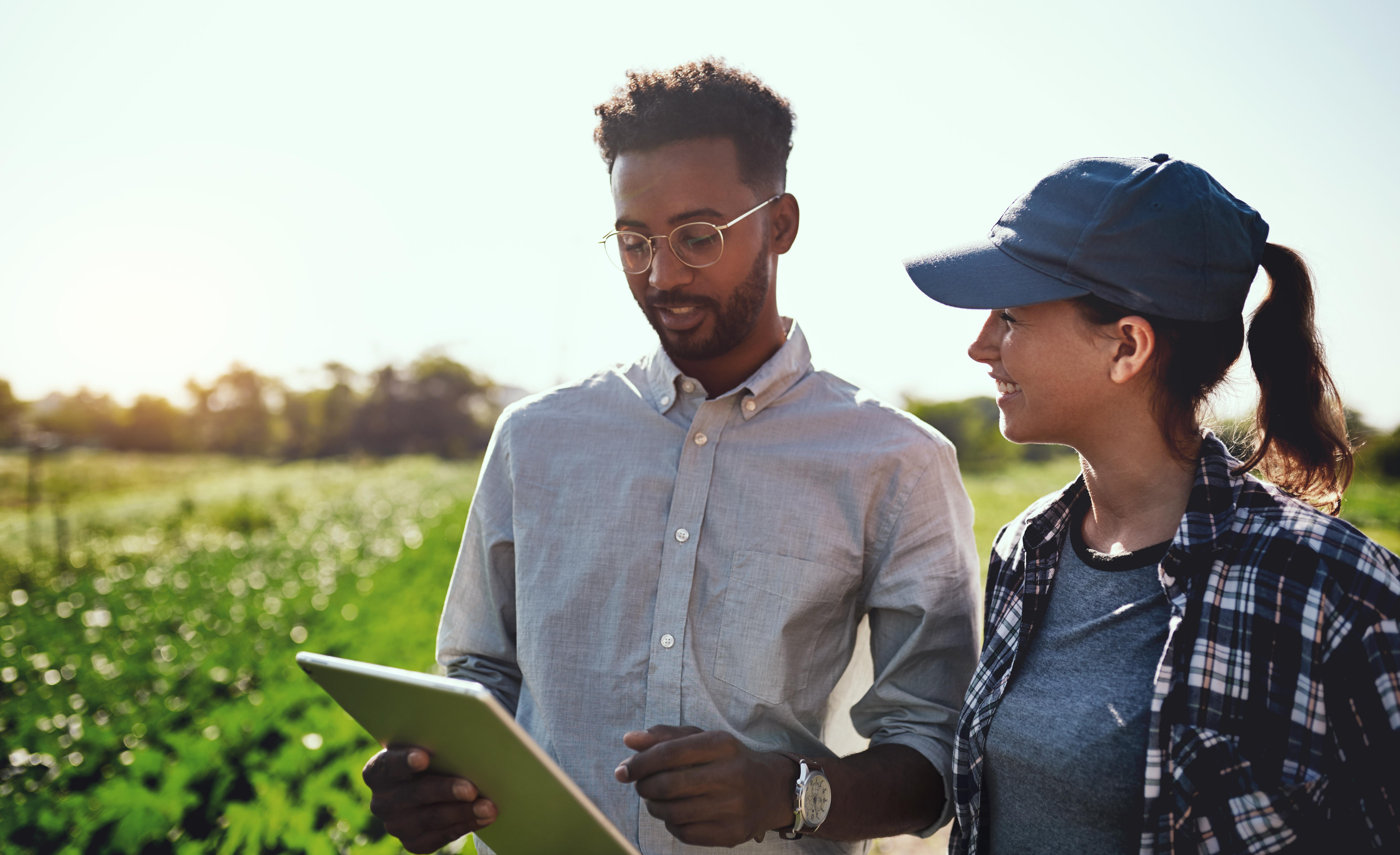 Two people walking and talking in front of fields