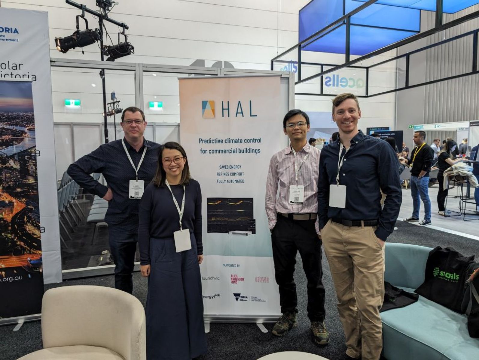 Staff members stand in front of a banner at a conference