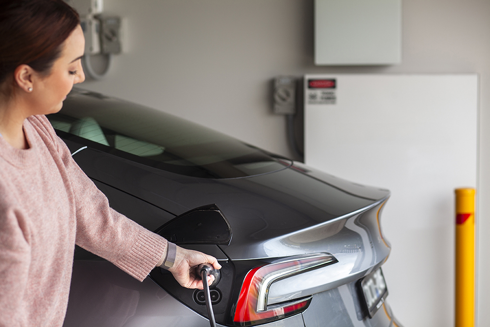 A female plugging in an electric vehicle charger