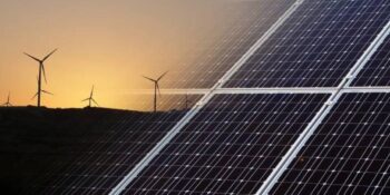 Solar panels with a windfarm in the distance  