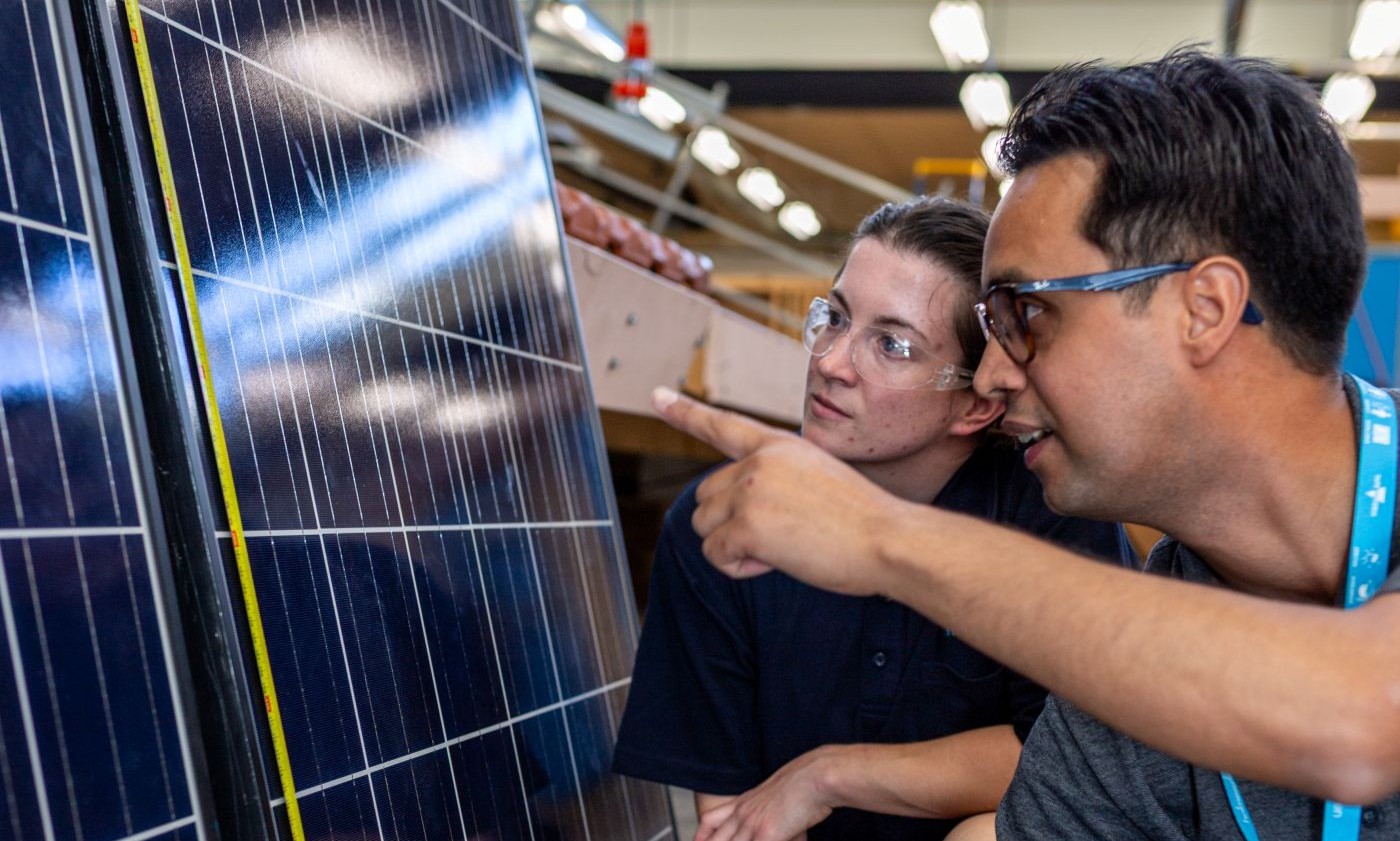 Two people inspecting a solar panel