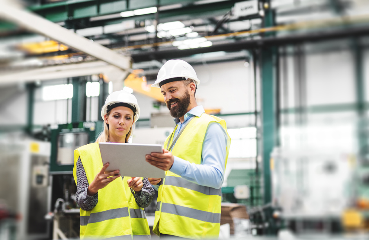 2 people in hard hats talking over plans