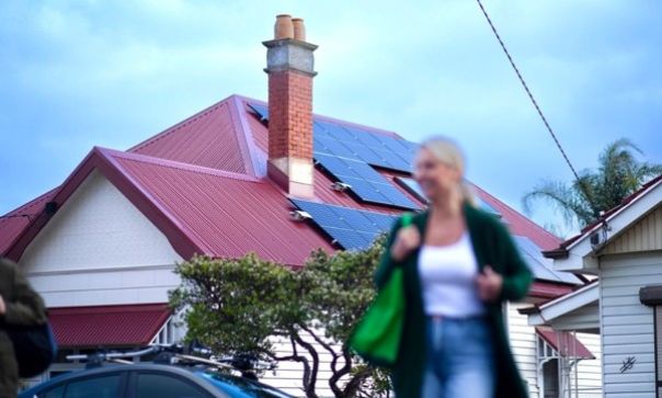 Residential house with a red metal roof equipped with solar panels, highlighting renewable energy adoption