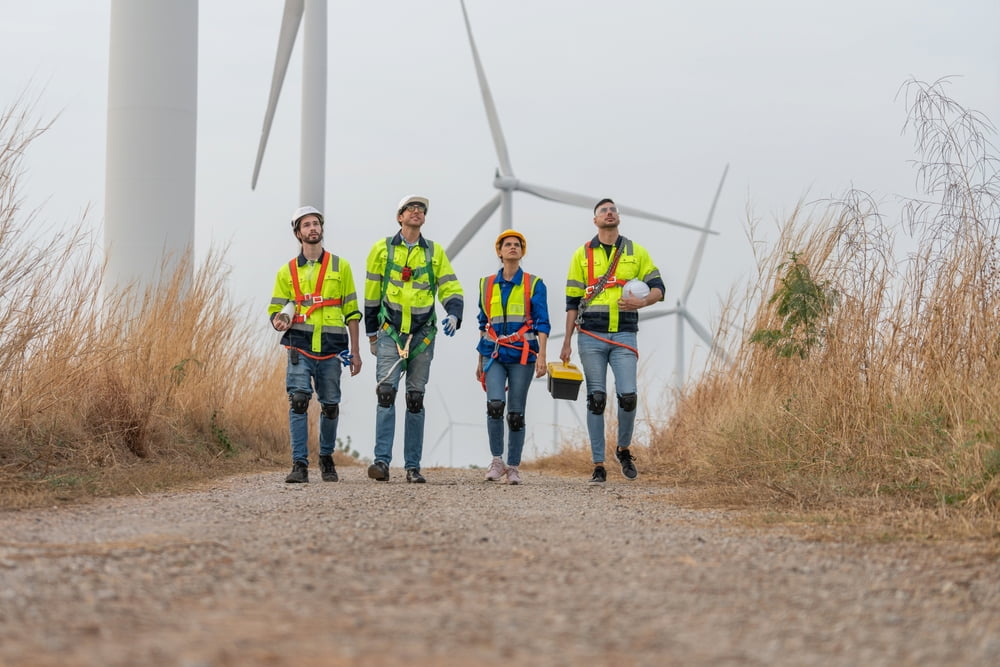 Workers walking on road with windfarm behind them  